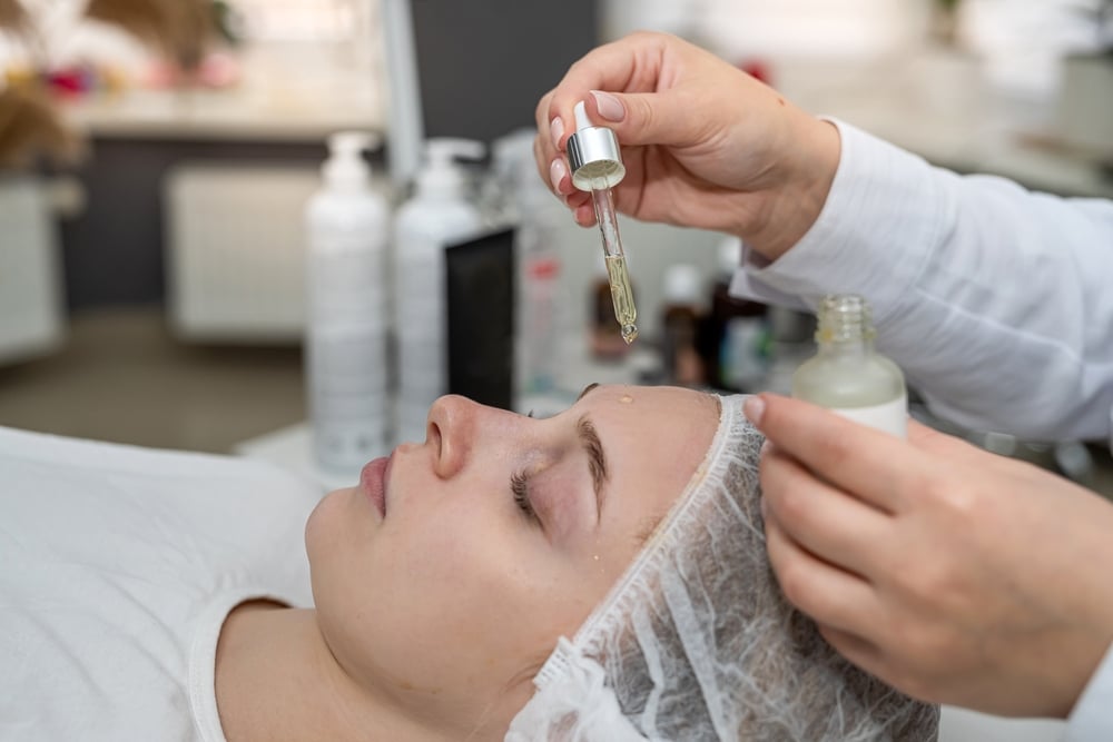 Image of a serum being applied to the face of a woman