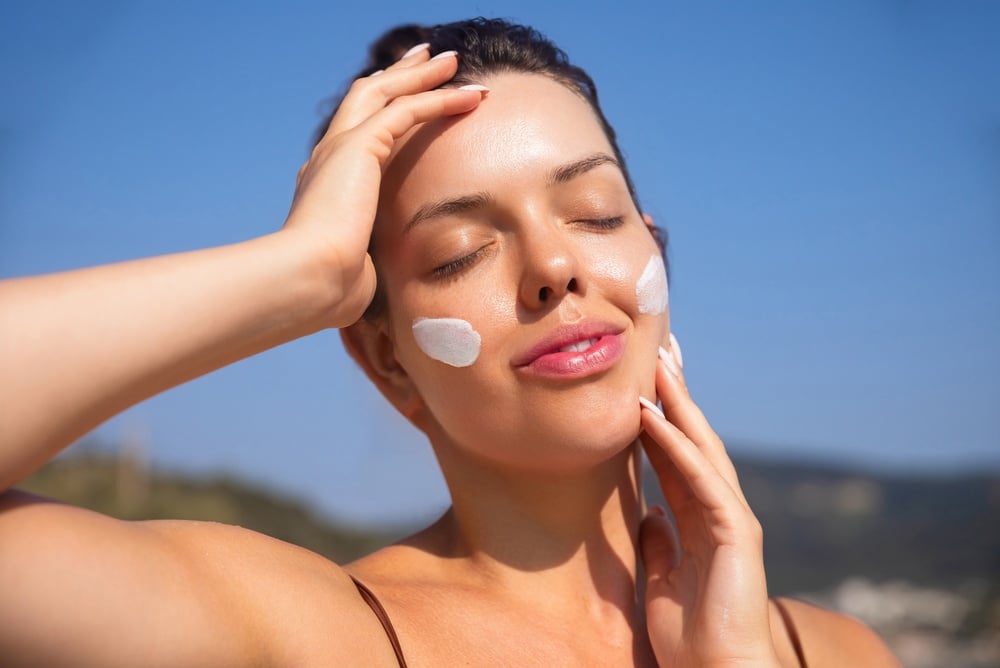 Image of woman with sun screen on her face under a sunny scene